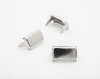 May include: Three silver metal rectangular-shaped rivets with a pointed end. The rivets are used for attaching fabric or leather.