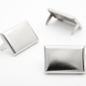 Puede incluir: Tres piezas de herrajes decorativos rectangulares de metal plateado con esquinas redondeadas. Las piezas tienen un acabado brillante y están diseñadas para ser utilizadas como adornos de muebles o manualidades.