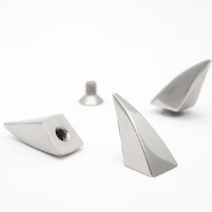 Peut inclure: Trois pointes triangulaires en métal argenté avec un filetage de vis sur le fond.