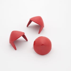 Pode incluir: Três protetores de móveis de plástico vermelho. Dois são em forma de cone com uma base plana e duas pontas. Um é em forma de cúpula redonda com uma base plana.