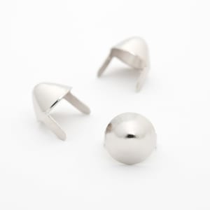 以下が含まれることがあります： 白い表面に置かれた、2本のピンが付いた円錐形の銀色の金属製スタッドが3つあります。