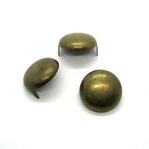 Puede incluir: Tres clavos de metal de color dorado antiguo, en forma de cúpula, con un extremo puntiagudo.