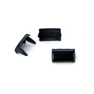 May include: Three small, black plastic components are arranged against a white background. Two are rectangular, and one has a unique, angled shape with two prongs. The items appear to be new.