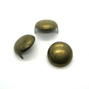 May include: Three antique gold-toned metal dome-shaped nailheads with a pointed end.