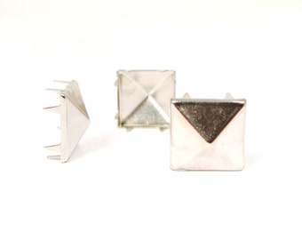 May include: Three silver pyramid-shaped studs with a pointed top and a square base. The studs have a shiny finish and are designed for use in crafts and DIY projects.