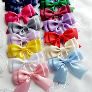Peut inclure: Une collection de nœuds en satin colorés dans diverses nuances, dont le rose, le bleu, le vert et le jaune. Les nœuds sont disposés sur une surface blanche texturée, mettant en valeur leurs couleurs vives et leur design élégant. Ces nœuds sont adaptés aux accessoires pour cheveux ou aux projets d'artisanat.