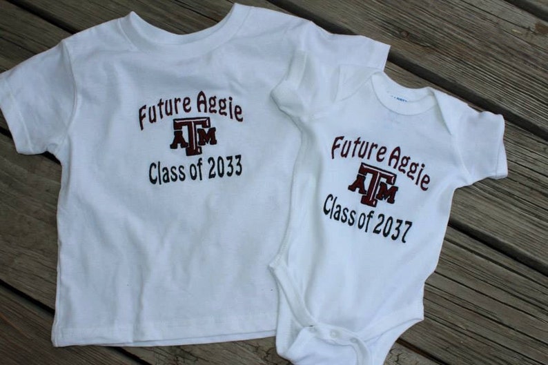 May include: Two white t-shirts with the text "Future Aggie" and "Class of 2033" and "Class of 2037" in maroon. The shirts have the Texas A&M logo. One is a toddler t-shirt, and the other is a baby onesie.