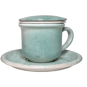 Può includere: Un set da tè in ceramica blu chiaro con tazza e piattino e coperchio. La tazza e il piattino hanno una smaltatura macchiata.