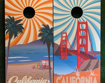 May include: Two wooden signs with a California theme. The left sign features a beach scene with palm trees and the text "California". The right sign features a red bridge with the text "CALIFORNIA".