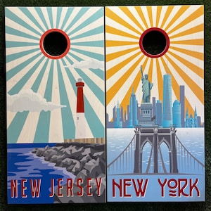 May include: Two wooden signs with a sunburst design. The left sign says "New Jersey" and features a lighthouse. The right sign says "New York" and features the Brooklyn Bridge.