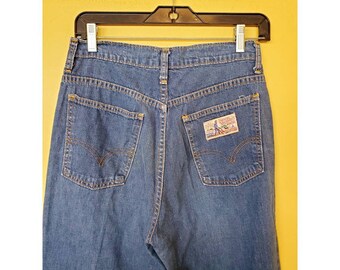 May include: A pair of dark blue denim jeans with a small embroidered patch on the back right pocket. The patch features a cartoon image of a man working on a farm.