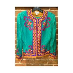 May include: A teal green silk jacket with a gold chain and jewel design. The jacket has a button closure and long sleeves. The label reads "Carolyn  Papell".