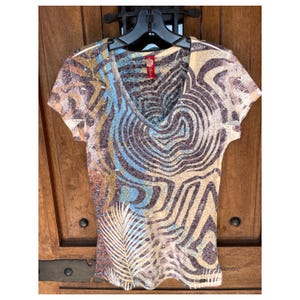 May include: A short-sleeved, V-neck shirt with a brown, blue, and white abstract print. The shirt has a relaxed fit and is made of a soft, comfortable fabric.