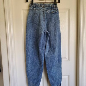 May include: A pair of light blue high-waisted jeans with a button fly and a belt loop closure. The jeans have a faded and distressed look.