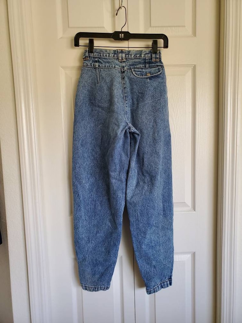 May include: A pair of light blue high-waisted jeans with a button fly and a belt loop closure. The jeans have a faded and distressed look.