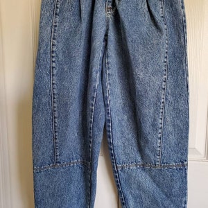 May include: A pair of light blue denim jeans with a distressed look. The jeans have a high waist and a relaxed fit. They feature a pleated front and a straight leg.