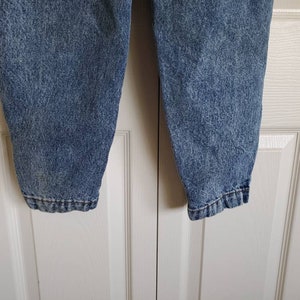 May include: A pair of blue denim jeans with a faded, speckled pattern. The jeans have a straight leg and a relaxed fit.