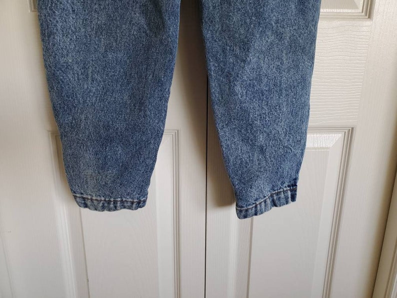 May include: A pair of blue denim jeans with a faded, speckled pattern. The jeans have a straight leg and a relaxed fit.