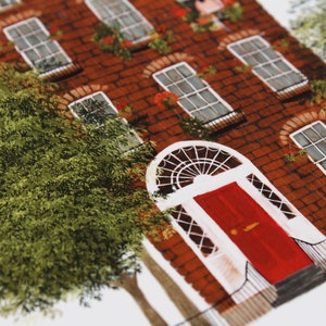 May include: A red brick building with a red door and white trim. The building has several windows with white trim and green plants growing in pots on the windowsills. There is a tree in the foreground.