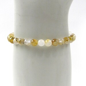 May include: A bracelet made of small, round, clear and yellow beads. The beads are arranged in a pattern of alternating colours.