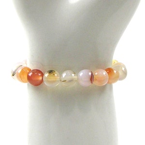 May include: A bracelet made of carnelian, agate and white agate beads. The beads are round and have a natural, polished finish.