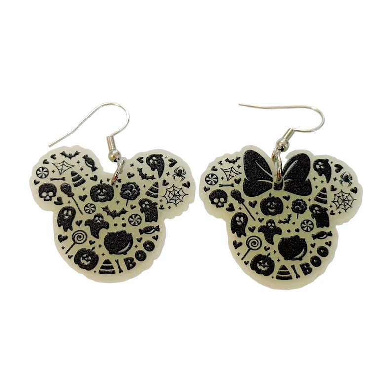 K&ouml;nnte beinhalten: Ein Paar im Dunkeln leuchtende Ohrringe in Form von Mickey-Maus-Ohren. Die Ohrringe sind mit schwarzen Halloween-Motiven verziert, darunter Geister, K&uuml;rbisse, Flederm&auml;use und Mais. Der rechte Ohrring hat eine schwarze Schleife oben.