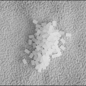 May include: A pile of small, white, plastic, cylindrical beads.