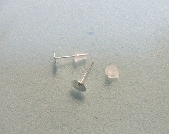 May include: Two silver earring posts with clear plastic backs. The posts are round and have a flat surface on one end.