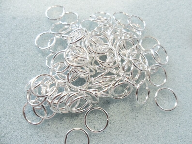 Puede incluir: Un mont&oacute;n de anillas de salto plateadas, un tipo de hallazgo de joyer&iacute;a utilizado para conectar cadenas, cordones y otros componentes de joyer&iacute;a.