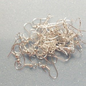 May include: A pile of silver earring hooks, a common jewelry making supply.