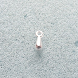 May include: A silver teardrop-shaped charm with a small loop at the top.