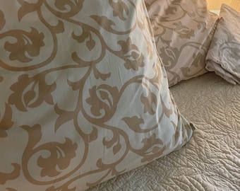 european size pillows. classic scroll design. blush pink or pale blue background with taupe scrolling