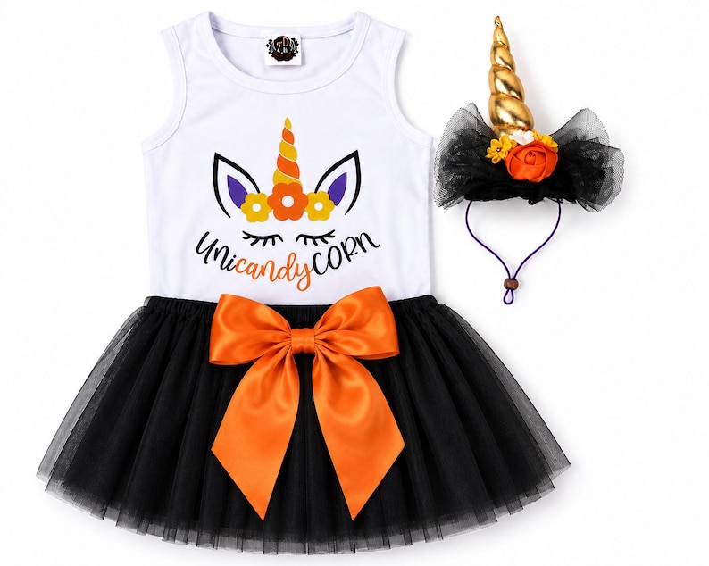 May include: A white sleeveless dress with a graphic of a unicorn face and the text Unicandy Corn, featuring a black tulle skirt with a large orange satin bow at the waist, accompanied by a matching headband with a gold unicorn horn and flowers.