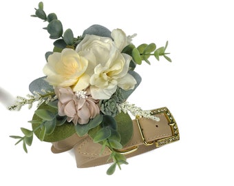 Op de afbeelding: Een beige leren hondenhalsband met een gouden gesp versierd met strass. De halsband is versierd met een bloemstuk van witte en crèmekleurige rozen, roze bloemen en groene bladeren.