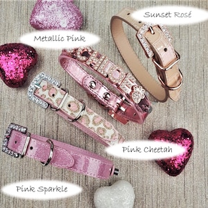 May include: Five different dog collars in pink and rose gold. The collars are decorated with rhinestones, glitter, and a cheetah print. The collars are labeled "Metallic Pink", "Pink Sparkle", "Pink Cheetah", "Sunset Ros&eacute;", and "Chole".