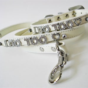 Könnte beinhalten: Halsband und Leine für Hunde aus weißem Leder mit Strasssteinen, die "I do too" buchstabieren, und einem Herz-Anhänger.
