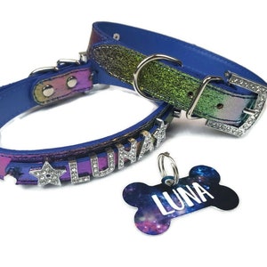 May include: A blue and iridescent dog collar with silver star and letter charms, spelling out "LUNA". A matching bone-shaped dog tag with a galaxy print and the name "LUNA" in white text.