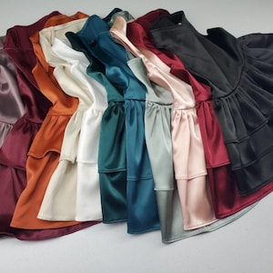 K&ouml;nnte beinhalten: Eine Sammlung von zehn R&uuml;schenblusen in verschiedenen Farben, darunter Burgunderrot, Orange, Beige, Wei&szlig;, T&uuml;rkis, Gr&uuml;n, Hellblau, Rosa und Schwarz.