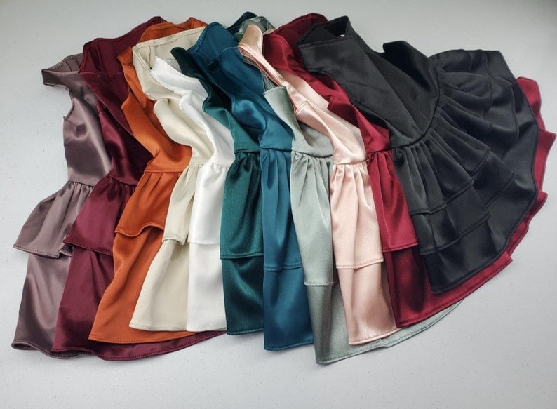 K&ouml;nnte beinhalten: Eine Sammlung von zehn R&uuml;schenblusen in verschiedenen Farben, darunter Burgunderrot, Orange, Beige, Wei&szlig;, T&uuml;rkis, Gr&uuml;n, Hellblau, Rosa und Schwarz.
