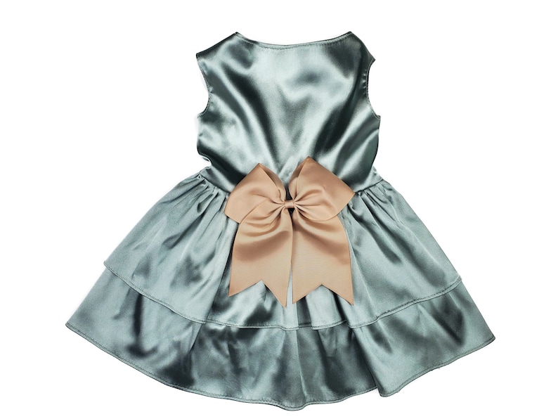 K&ouml;nnte beinhalten: Ein hellblaues Satin-Kleid mit einer gro&szlig;en braunen Schleife auf der R&uuml;ckseite.