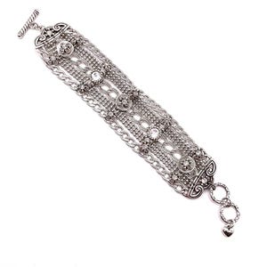 May include: Silver-toned bracelet featuring multiple strands of chain and decorative elements. The bracelet includes floral and circular designs, with clear crystal accents. A toggle clasp secures the bracelet, and a heart charm dangles from the end.