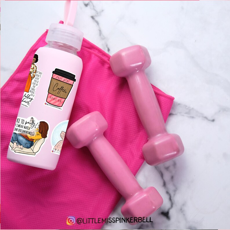 May include: A pink water bottle with stickers on it, including one that says "Coffee, I'm on it". The bottle is sitting on a pink towel with two pink dumbbells.
