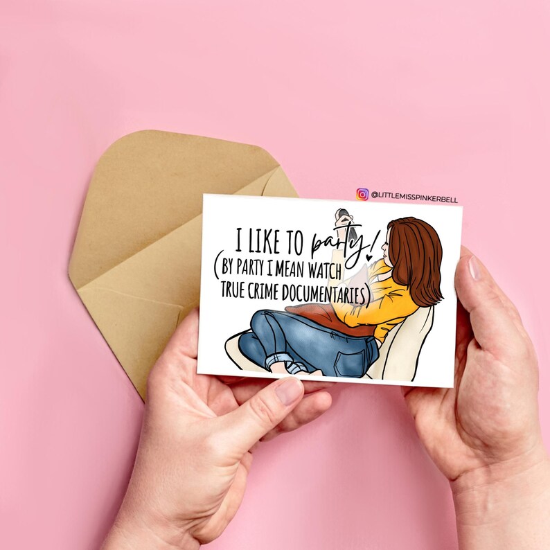 May include: A white card with a cartoon illustration of a person sitting on a couch and watching TV. The text on the card reads "I like to party! (By party I mean watch true crime documentaries)"