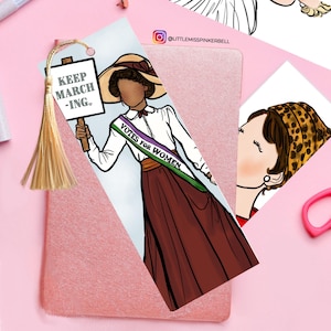 May include: A bookmark featuring a woman in a white shirt and brown skirt holding a sign that says "Keep Marching". She is wearing a sash that says "Votes for Women". The bookmark has a gold tassel.