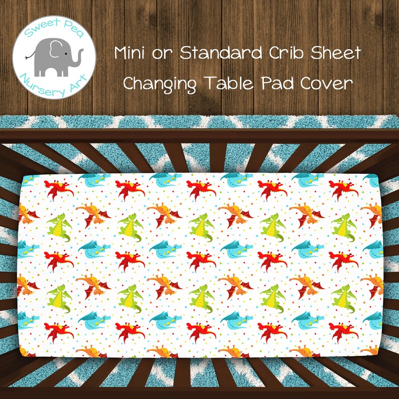 May include: A white crib sheet with a colorful dragon pattern. The sheet features red, orange, green, and blue dragons with polka dots. The text on the image reads "Mini or Standard Crib Sheet Changing Table Pad Cover."