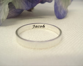 May include: A silver band ring with the name "Jacob" engraved on the inside.