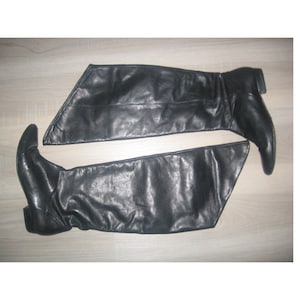 Könnte beinhalten: Ein Paar schwarze, kniehohe Stiefel aus Leder mit spitzer Zehenpartie.