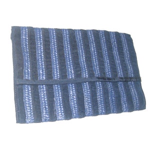 Puede incluir: Un bolso de mano rectangular con un patrón de rayas en tonos azules. Las rayas alternas crean una apariencia texturizada. El bolso tiene un cierre de solapa y está hecho de material textil.