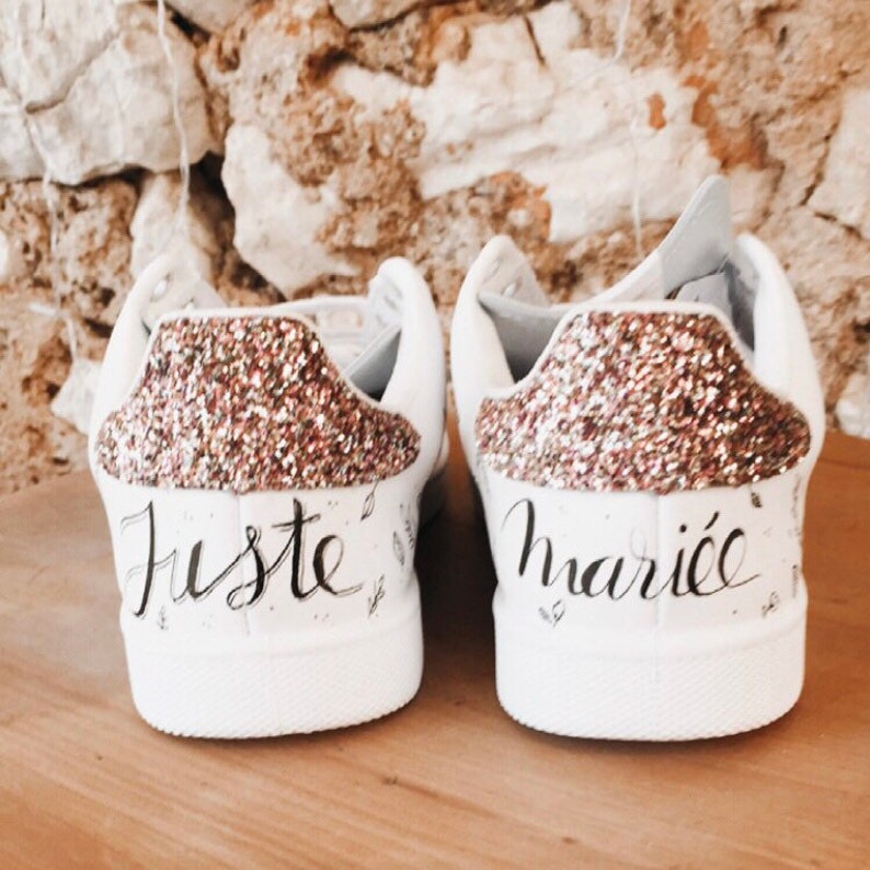 May include: A pair of white trainers with gold glitter on the back. One shoe says "Juste" and the other says "mari&eacute;e".