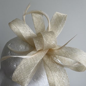 May include: A cream-coloured mesh bow with feathers, ideal for adding a touch of elegance to any outfit.